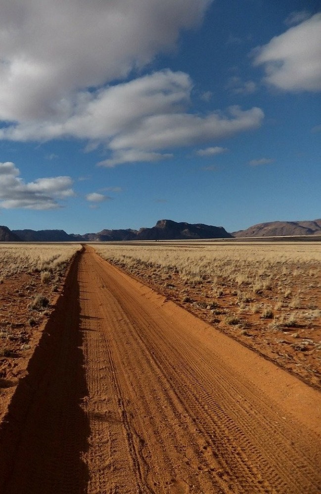 a straight, sandy track running to the hills in the distance